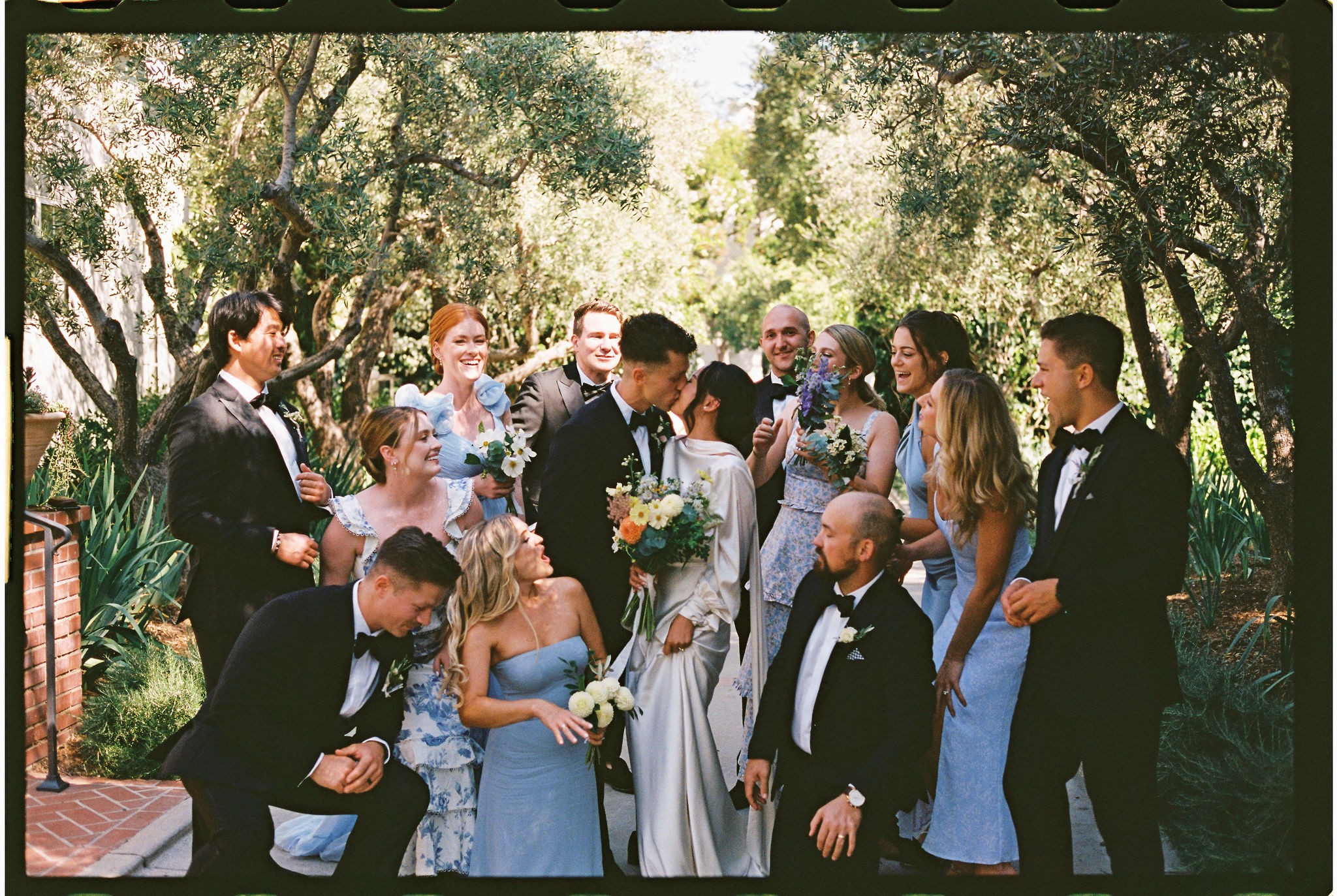 Bride and groom kiss as they take documentary style wedding photos with their bridal party