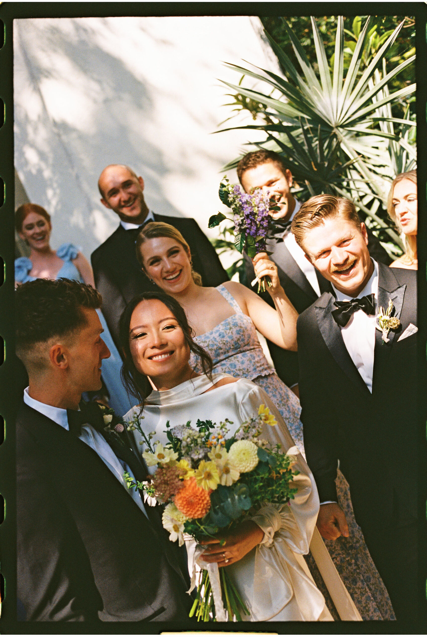 Bride and groom kiss as they take documentary style wedding photos with their bridal party