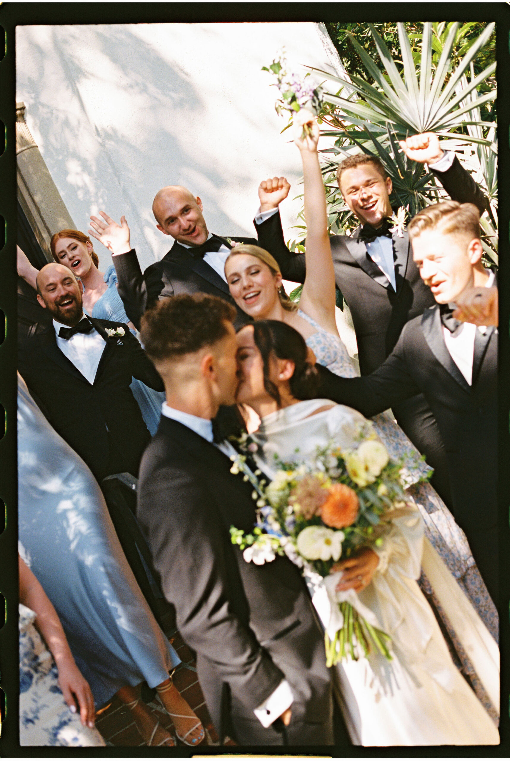 Bride and groom kiss as they take documentary style wedding photos with their bridal party