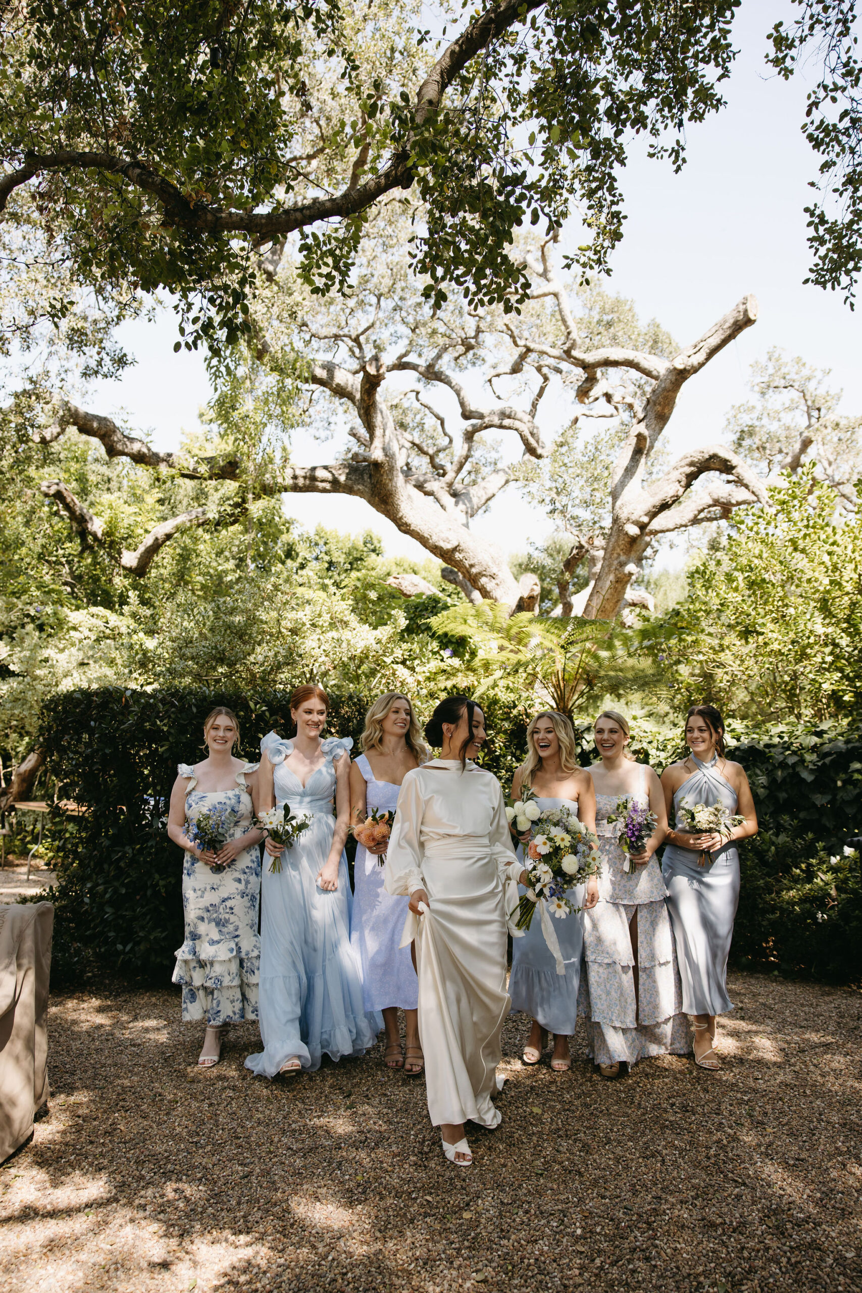 bridesmaids in colorful dresses pose for documentary style wedding photos outdoors