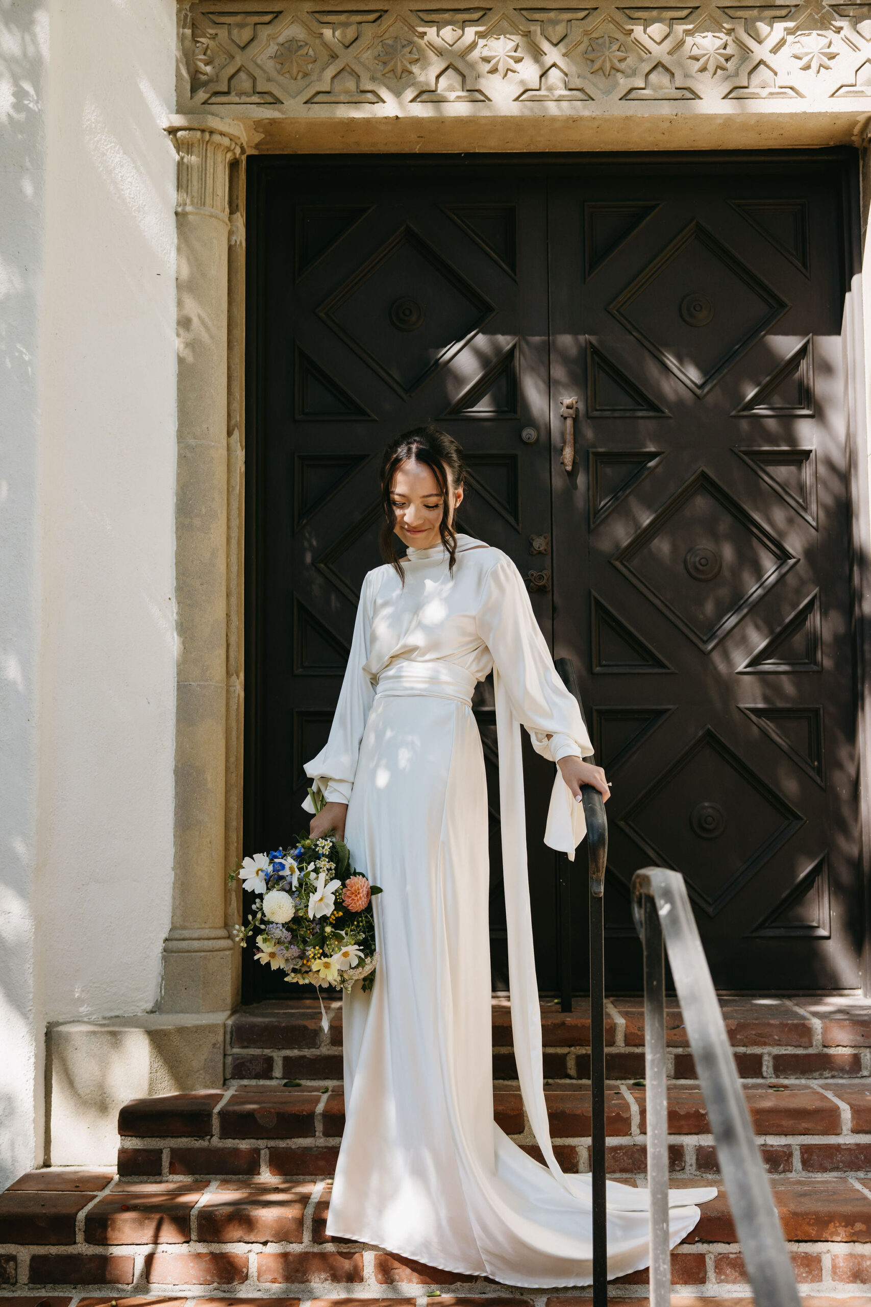 bride holding a bouquet walking down a staircase | documentary style wedding photos