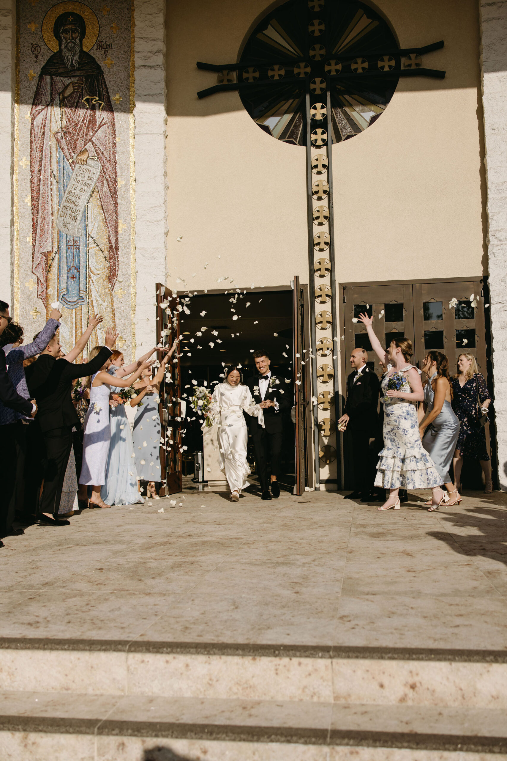 Bride and groom exiting their wedding ceremony while guests throw petals