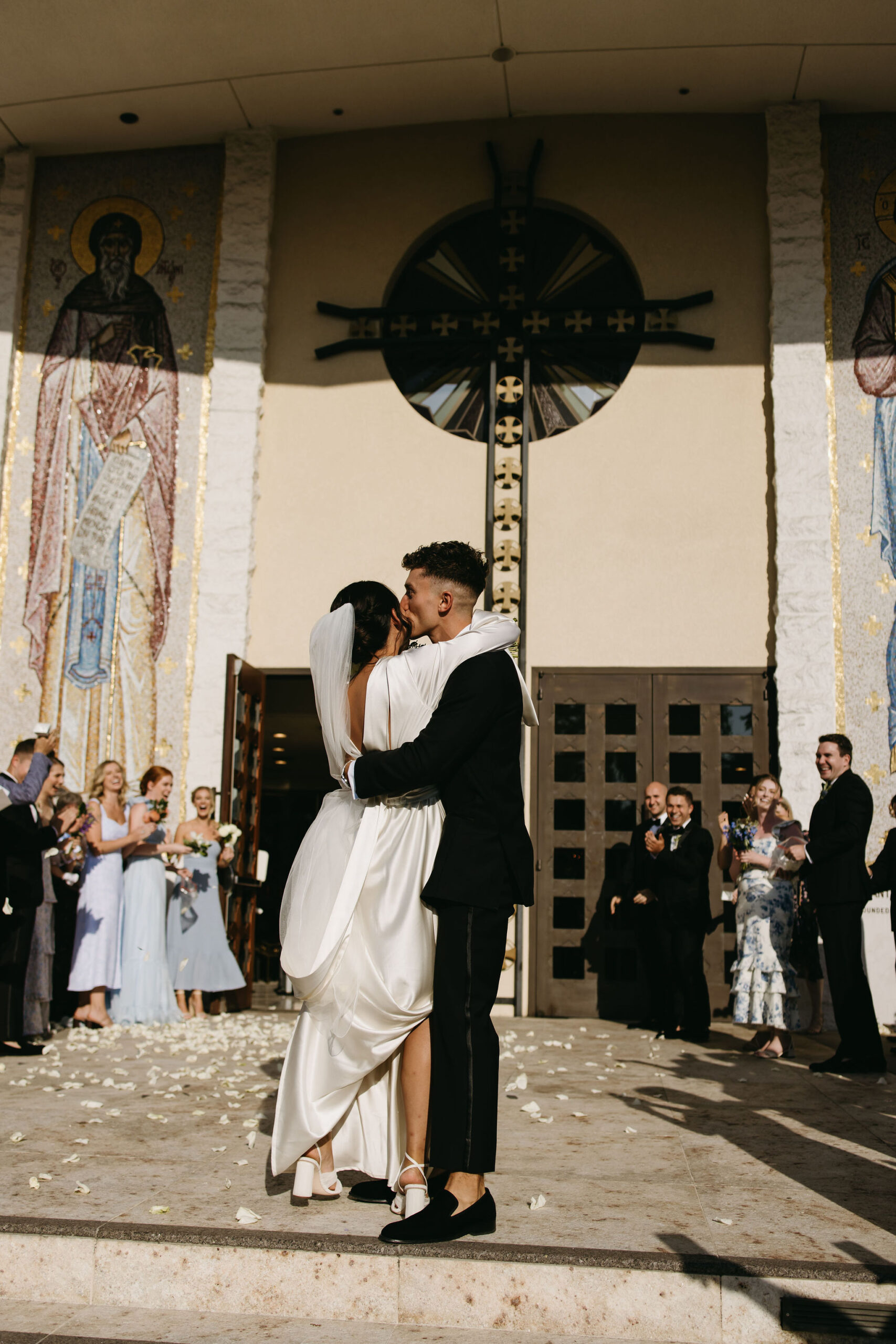 Bride and groom exiting their wedding ceremony while guests throw petals