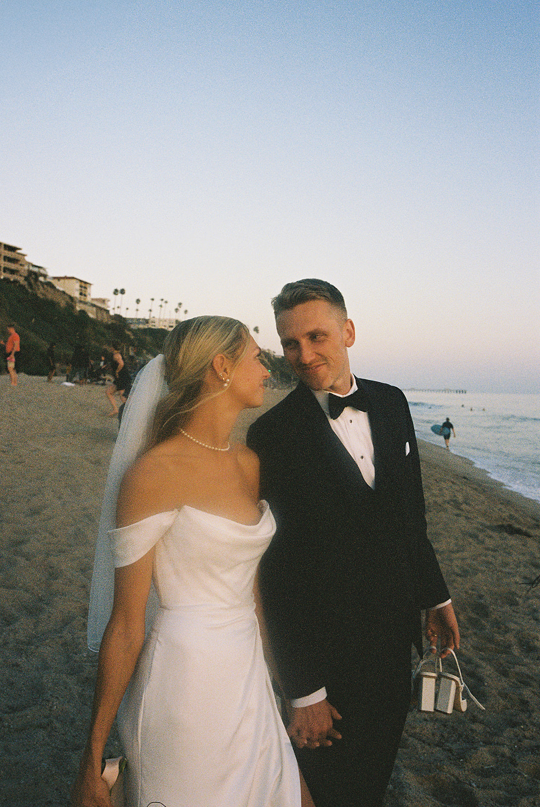 A bride and groom embrace and smile at each other against a soft, blurred background.