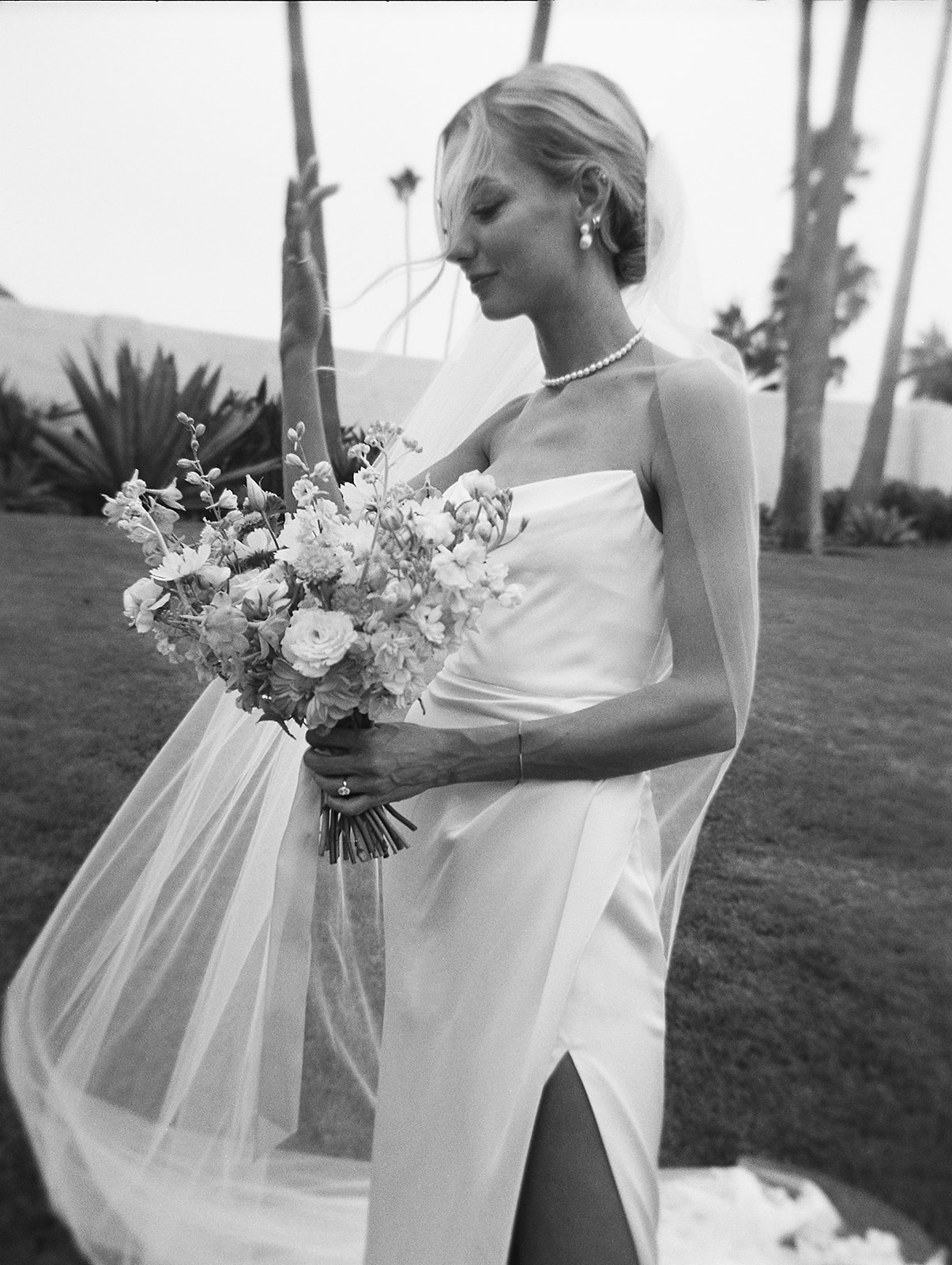 A bride and groom embrace and smile at each other against a soft, blurred background.