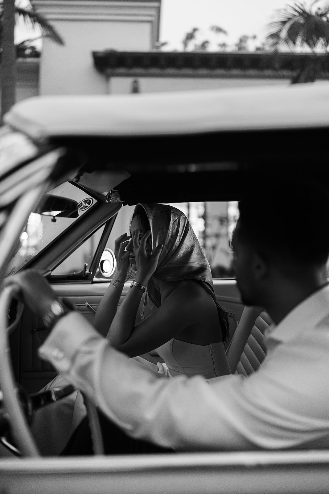 Bride and groom sit in a vintage convertible, the bride holding a bouquet. The lighting is dim, casting a warm glow inside the car for their santa barbara elopment