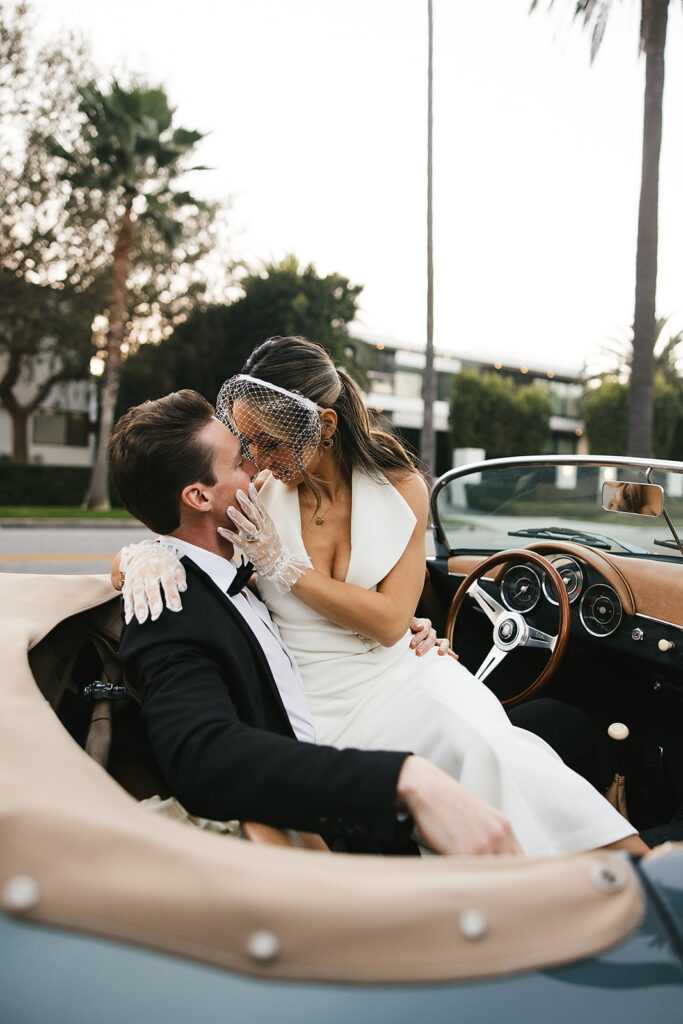 man and woman take engagement photos in LA outdoors by a vintage car