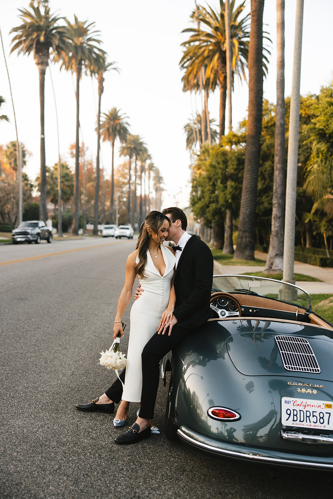 man and woman take engagement photos in LA outdoors by a vintage car