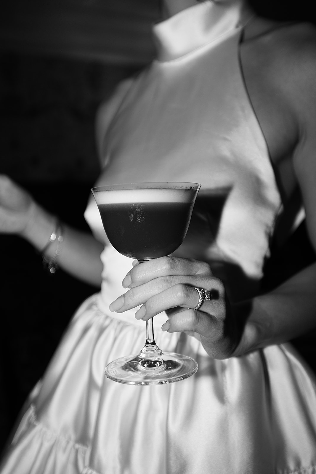 A couple in formal attire shares a dance in a restaurant with white tablecloths and dim lighting.