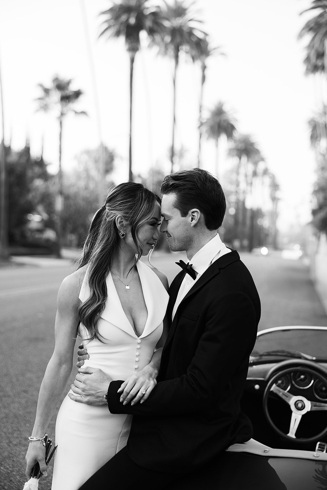 man and woman take engagement photos in LA outdoors by a vintage car