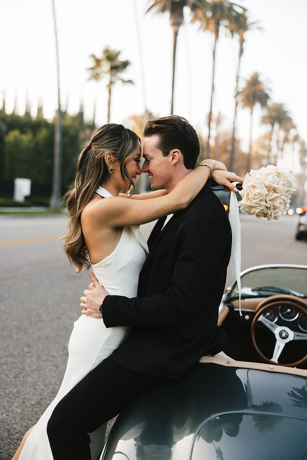 man and woman take engagement photos in LA outdoors by a vintage car