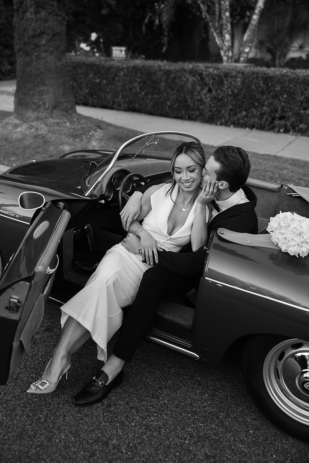 man and woman take engagement photos in LA outdoors by a vintage car