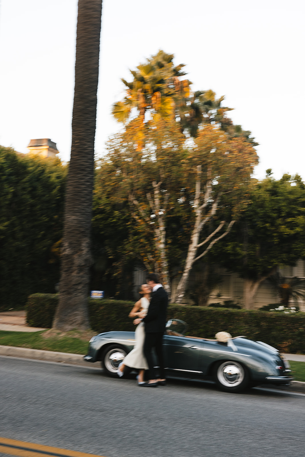 man and woman take engagement photos in LA outdoors by a vintage car