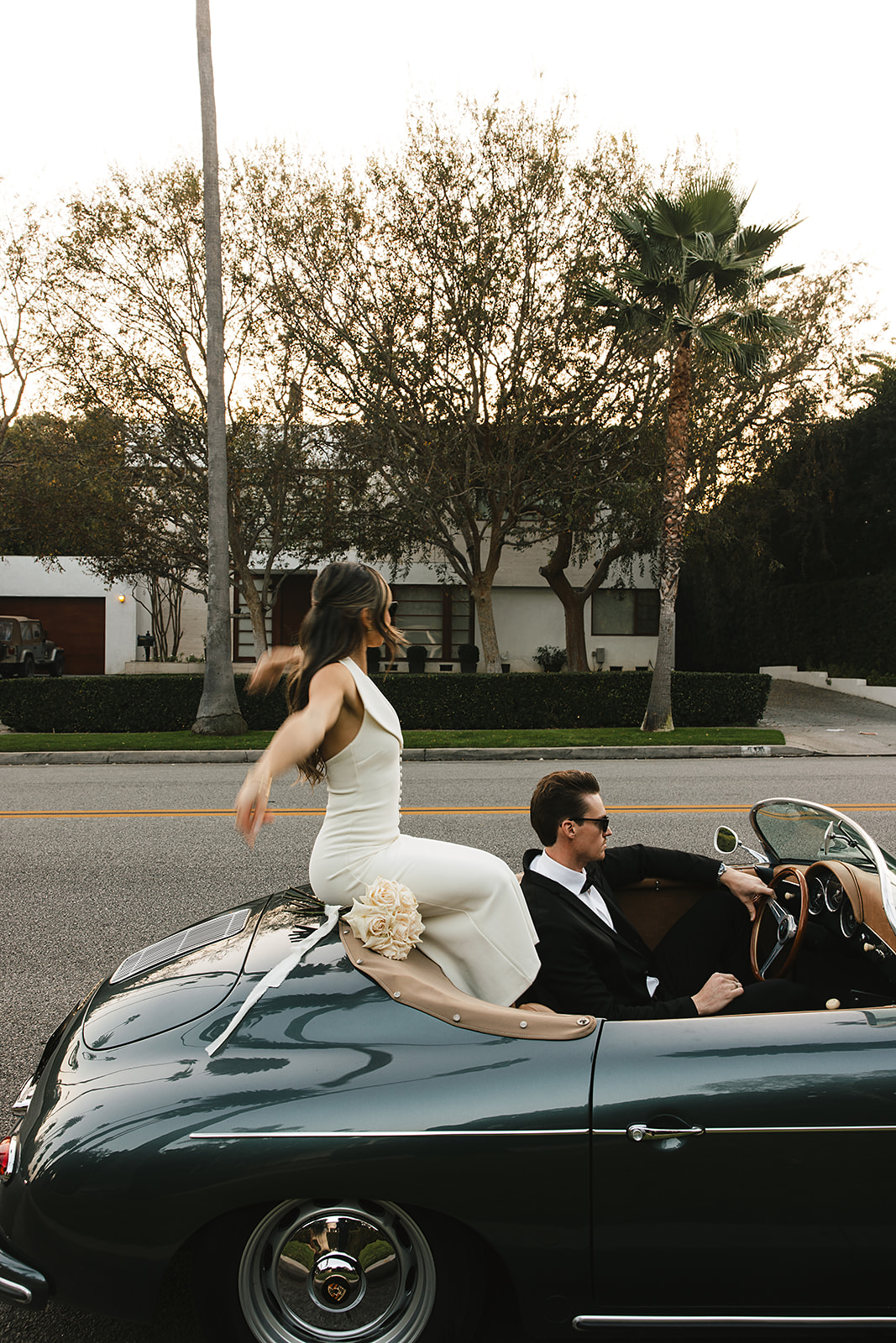 man and woman take engagement photos in LA outdoors by a vintage car