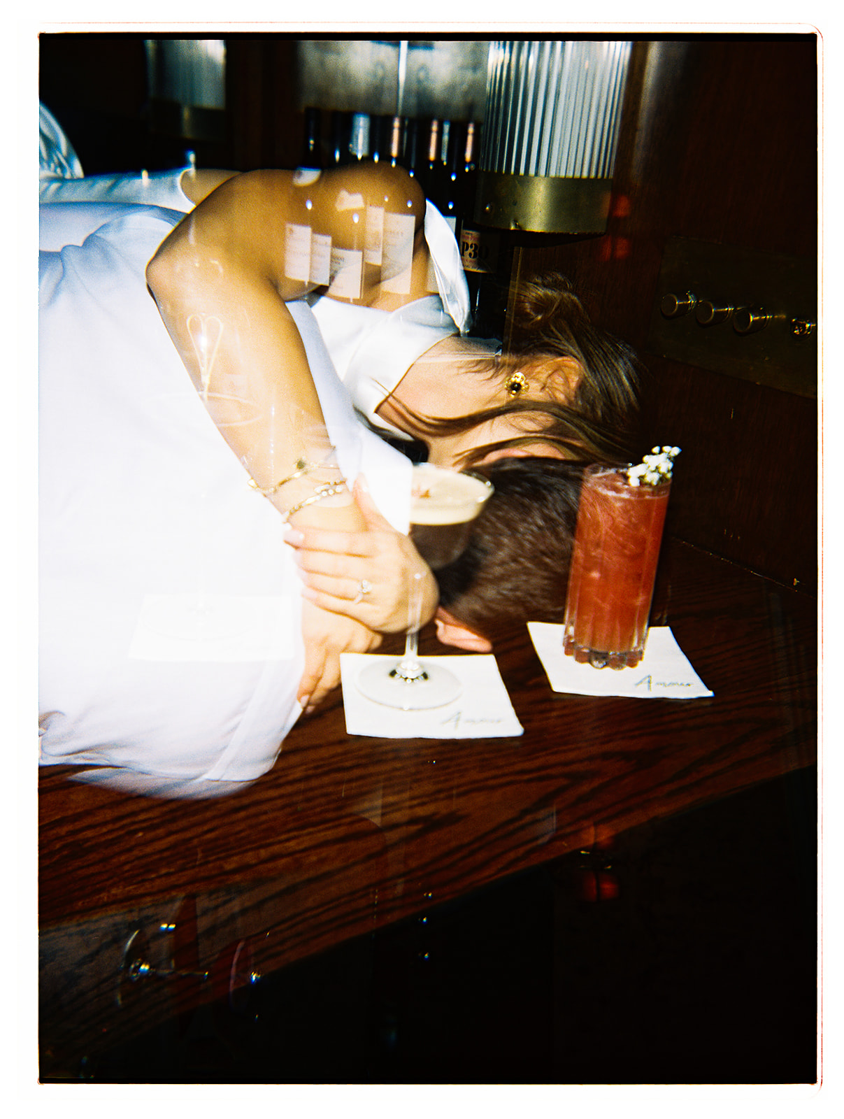 A couple in formal attire shares a dance in a restaurant with white tablecloths and dim lighting.