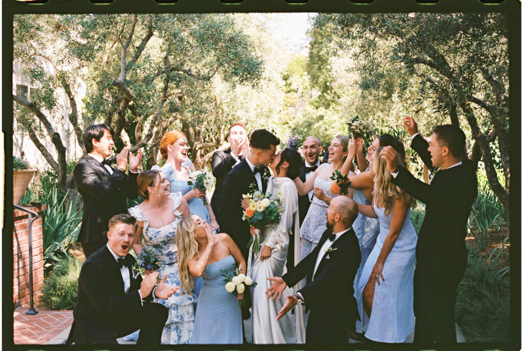 Bride and groom kiss as they take documentary style wedding photos with their bridal party 