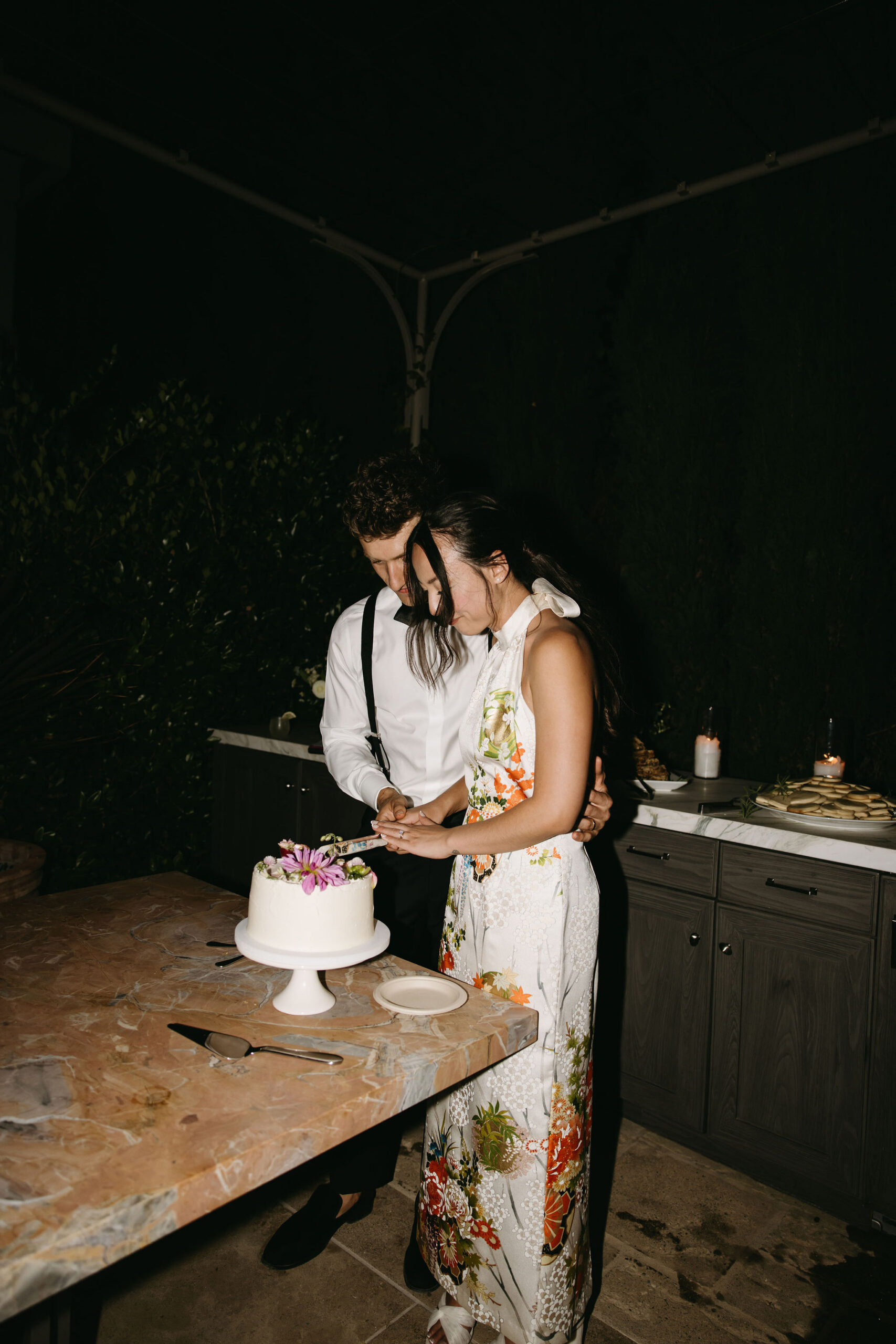 couple cuts cake at their wedding reception at a private residence for a backyard wedding 