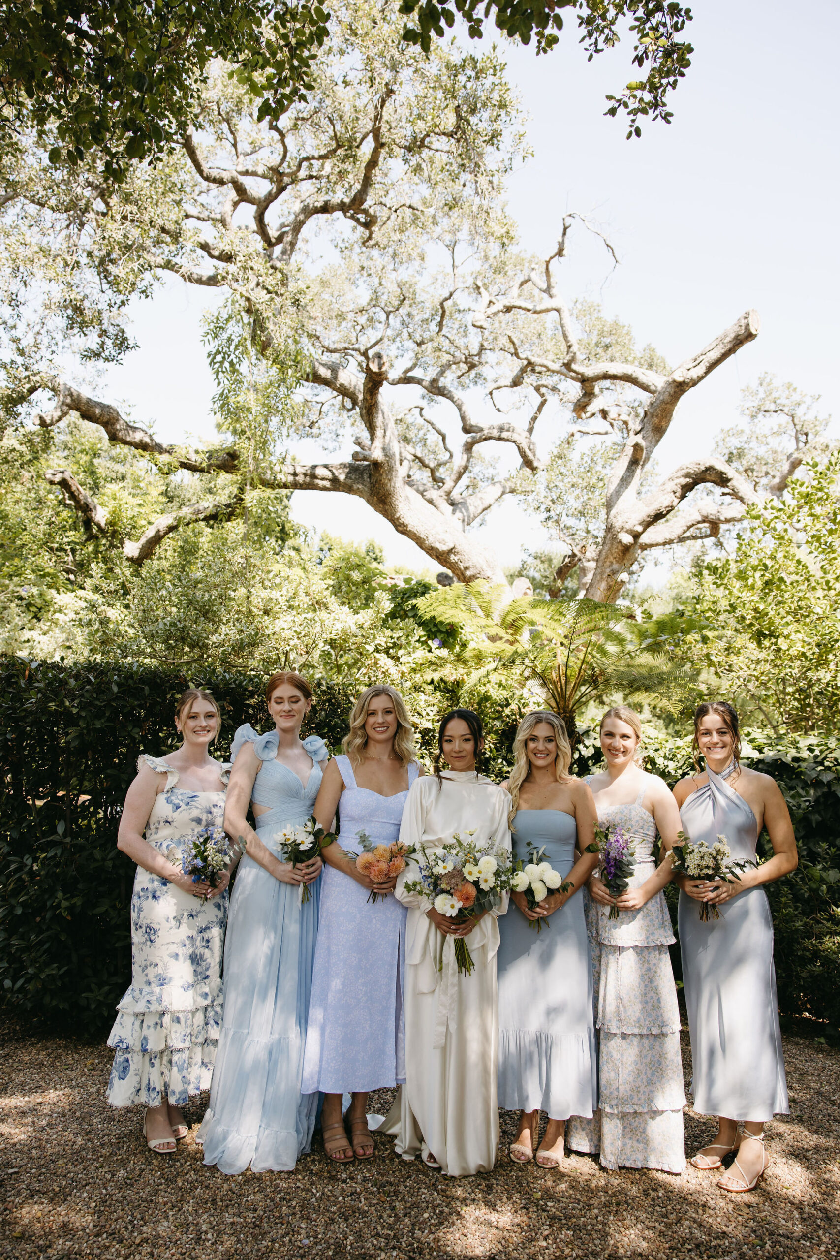 bridesmaids in colorful dresses pose for documentary style wedding photos outdoors