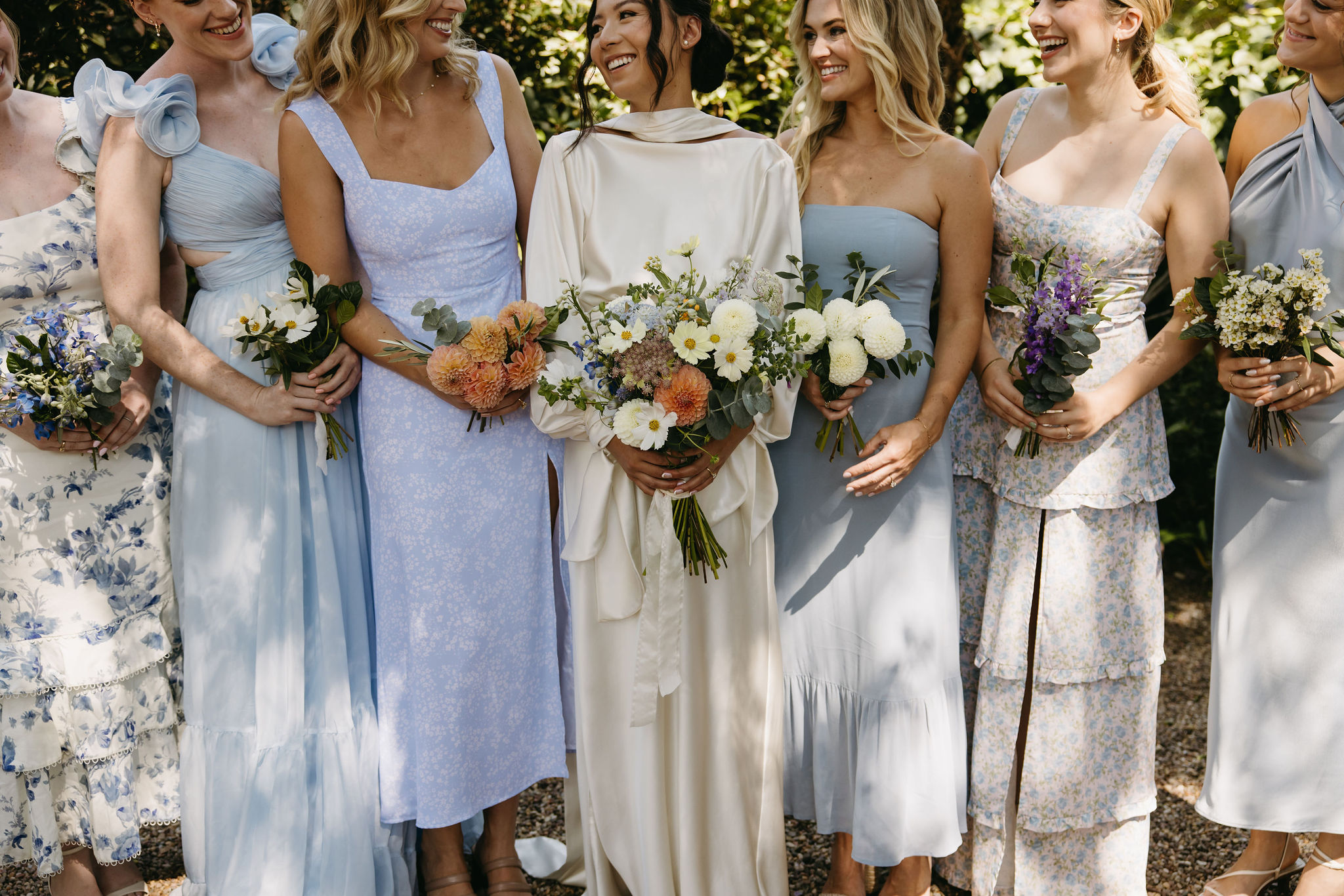 bridesmaids in colorful dresses pose for documentary style wedding photos outdoors