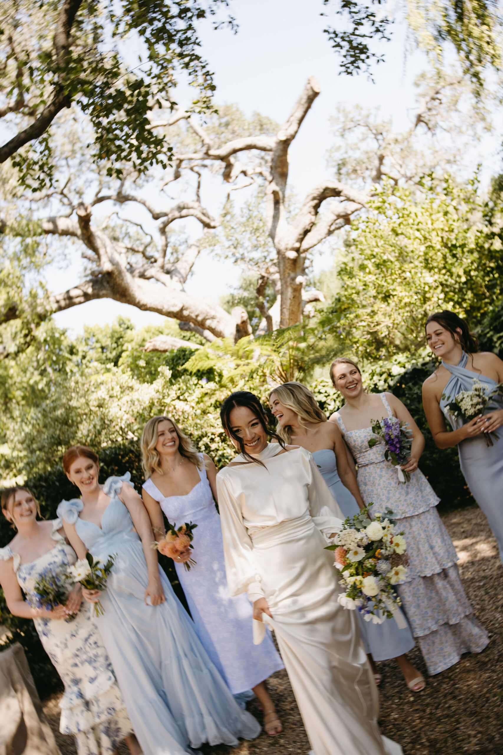 bridesmaids in colorful dresses pose for documentary style wedding photos outdoors