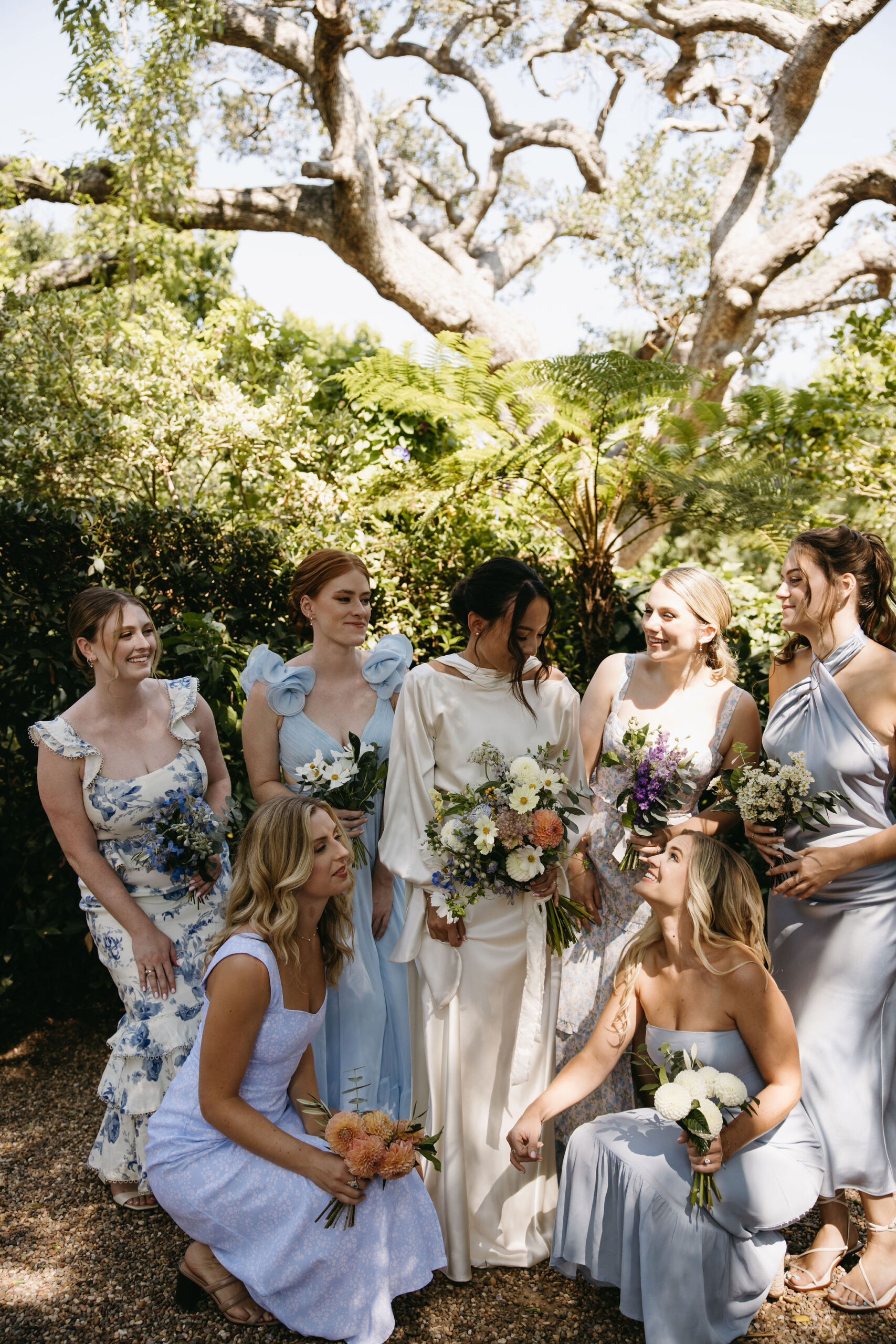 bridesmaids in colorful dresses pose for documentary style wedding photos outdoors