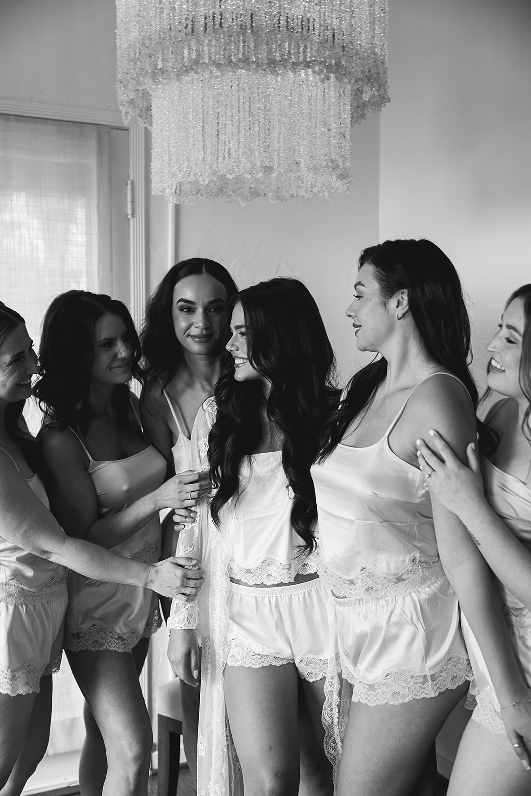 A group of bridesmaid in matching light blue attire pose indoors on a rug, with one holding a small dog for a wedding at the La Venta Inn