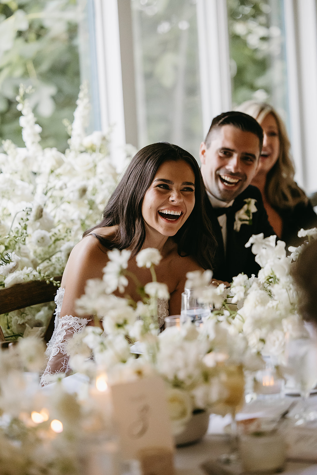 A woman and man sitting together at a floral-decorated table, smiling and laughing.